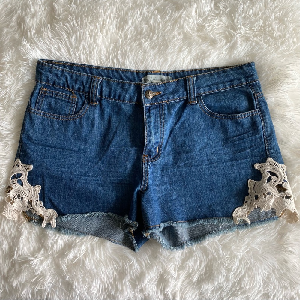 Altar’d State brand jean shorts with dark blue wash and crochet accents.